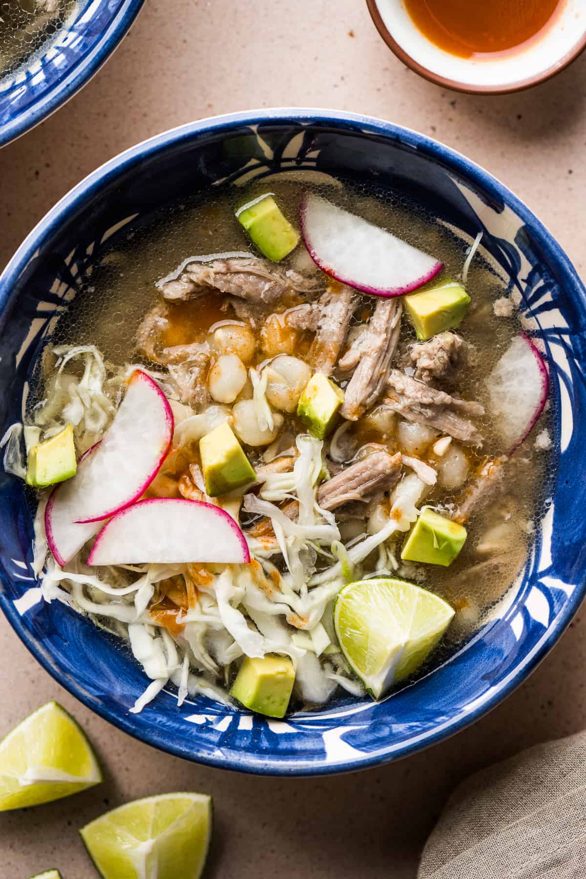 Pozole blanco in a bowl topped with avocado, radishes, and thinly sliced cabbage.