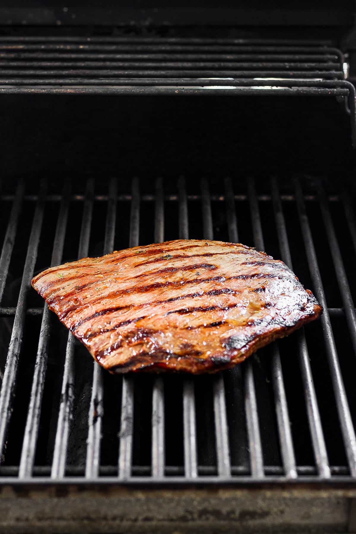 Flank steak placed on a grill until cooked through. 