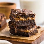 Dulce de Leche Brownies stacked on top of one another to showcase the layer of dulce de leche in the middle.