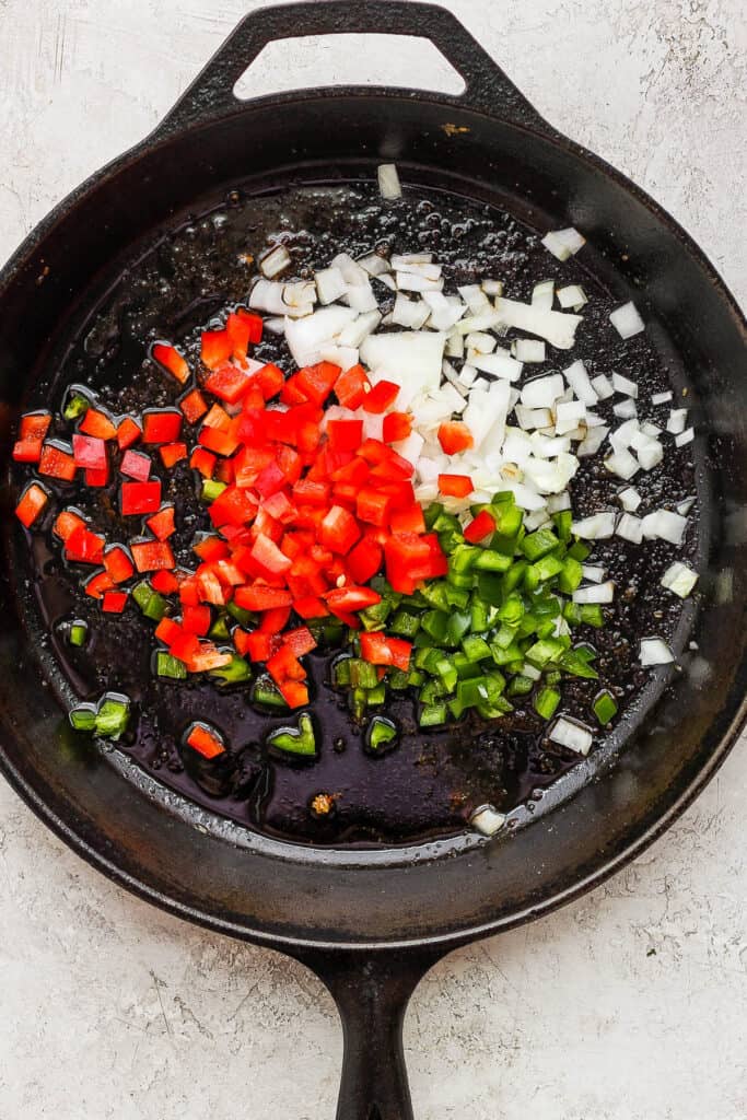 Peppers and onions cooking in a skillet.