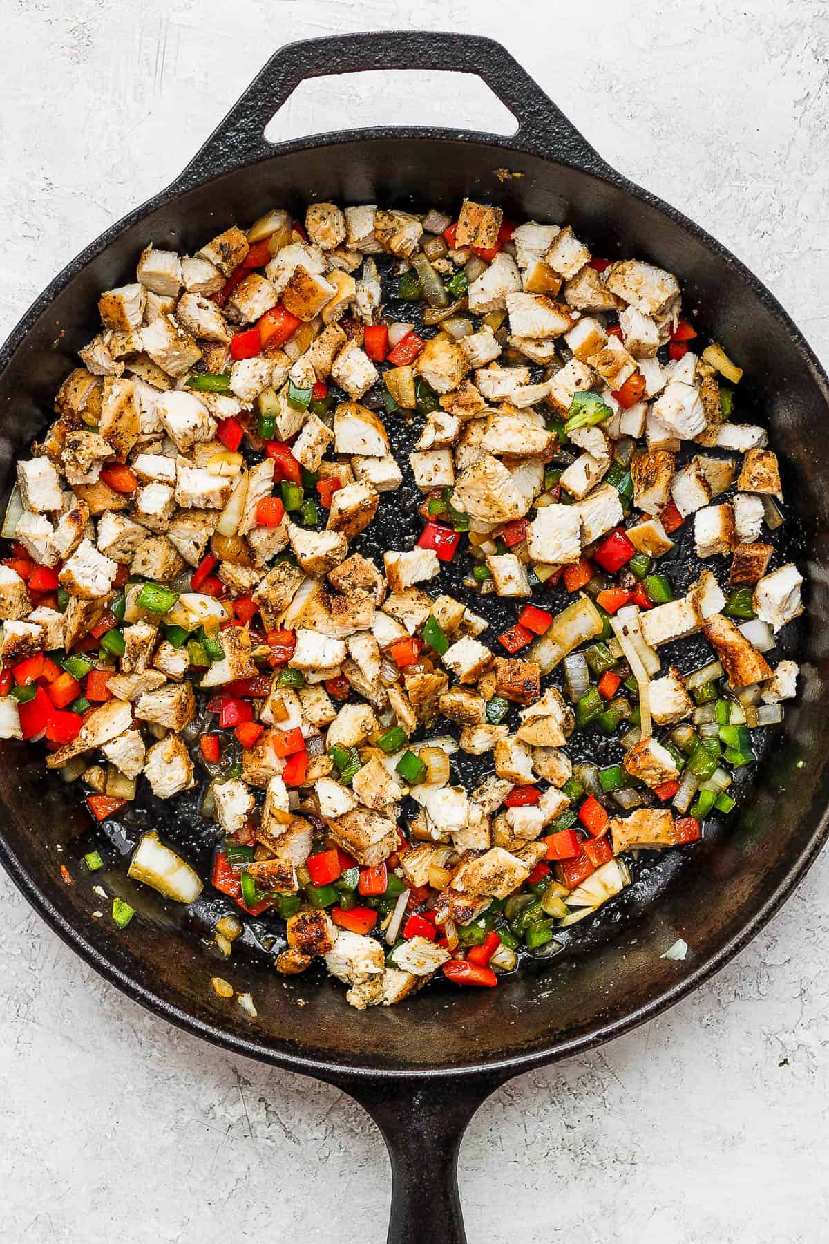 Chopped chicken, peppers, and onions in a skillet for chicken quesadillas.