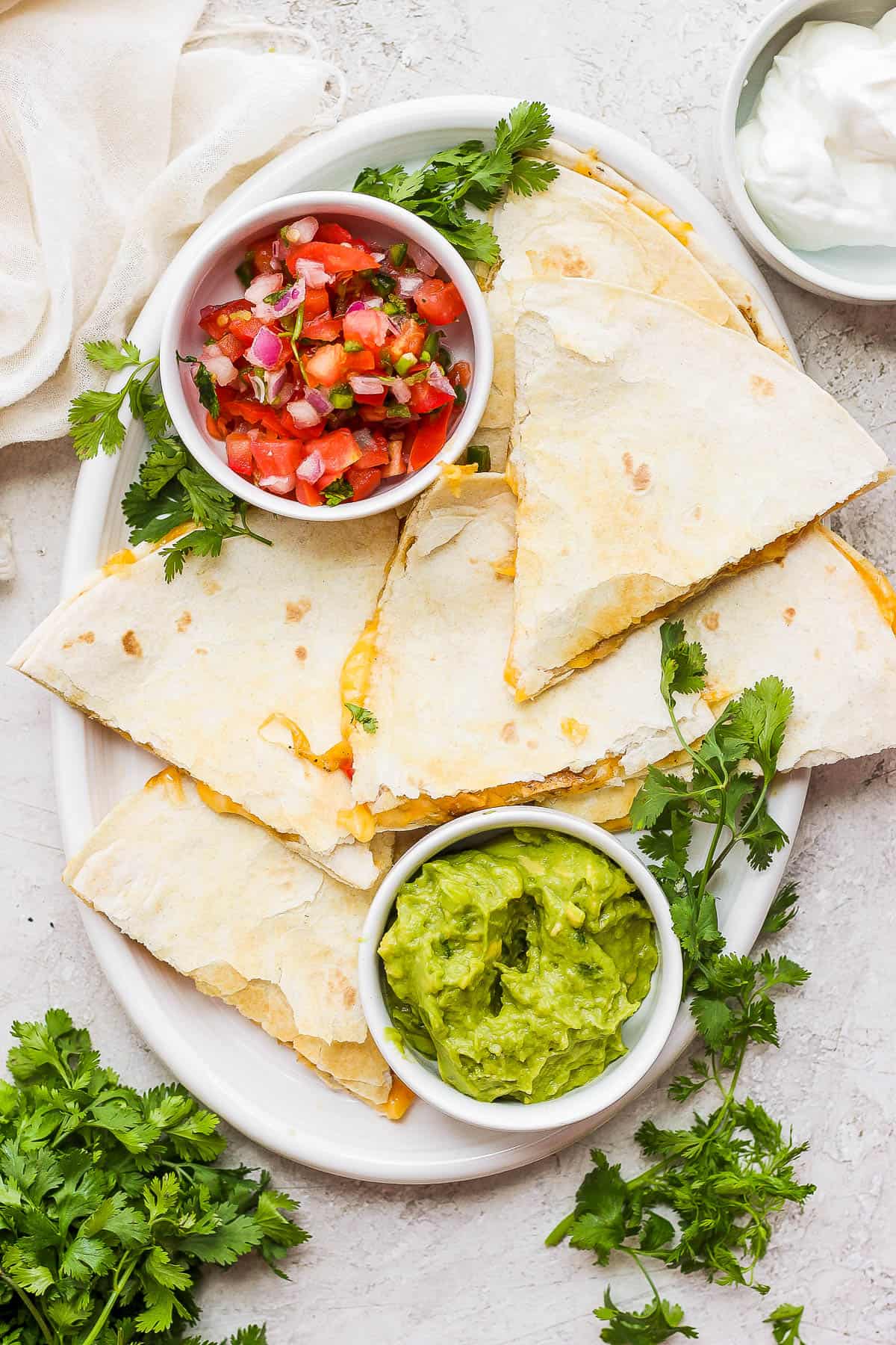 A plate of chicken quesadillas served with a side of pico de gallo and guacamole.