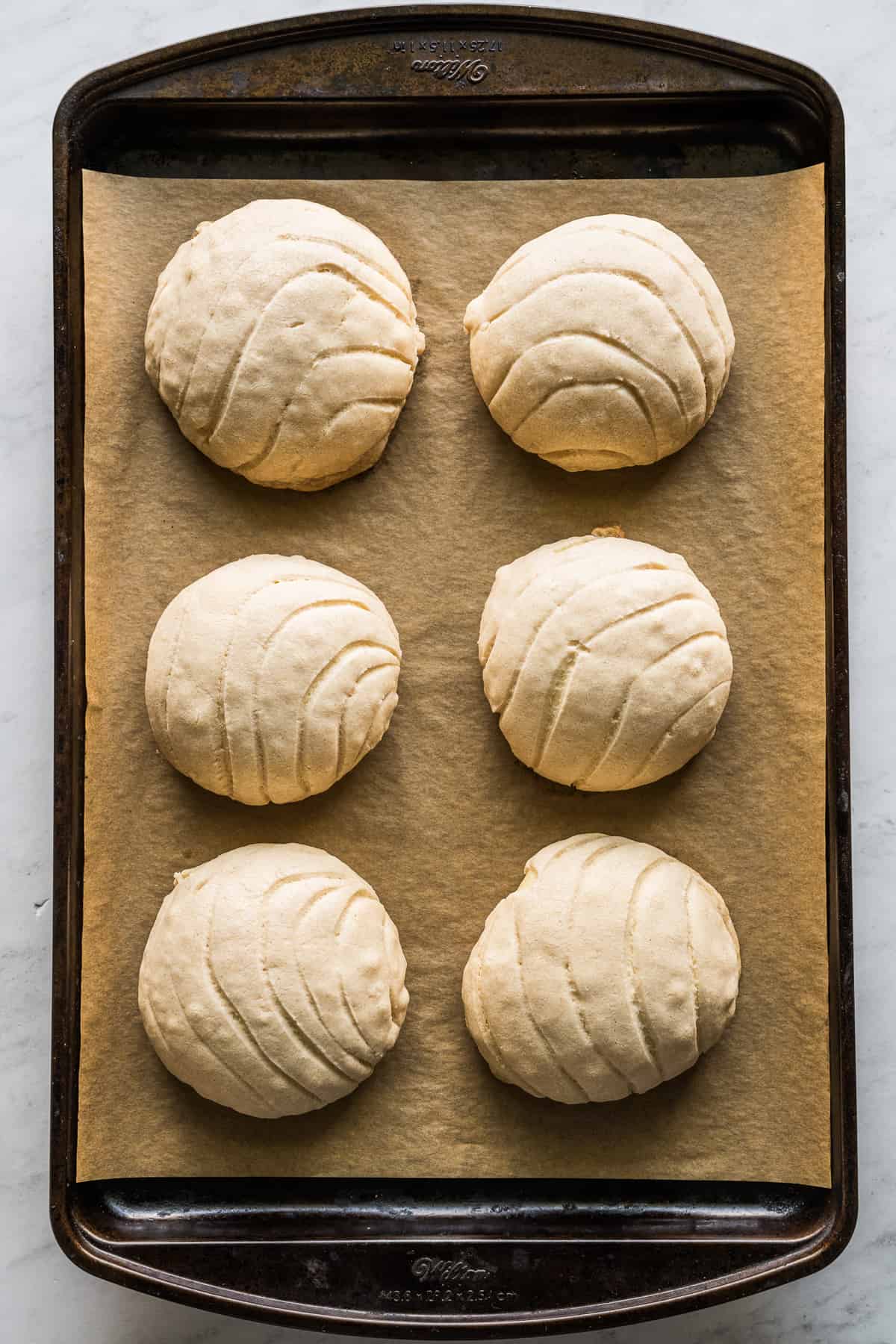 Baked maple conchas on baking sheet lined with parchment paper.