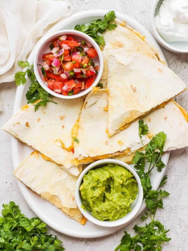 A plate of chicken quesadillas served with a side of pico de gallo and guacamole.