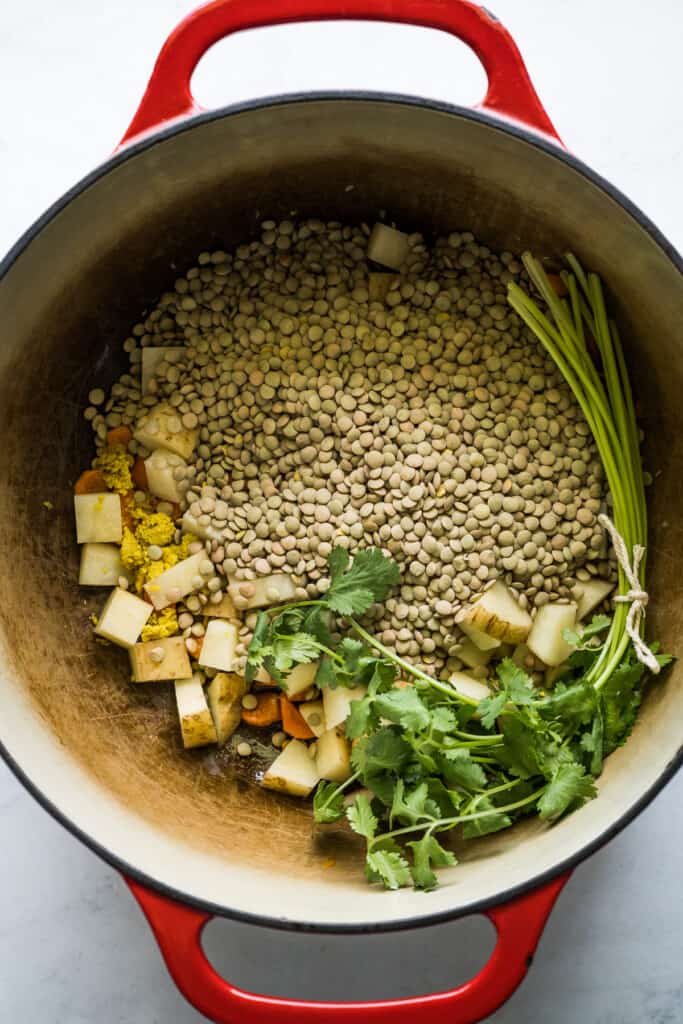 Lentils, potatoes, carrots, and cilantro in a pot.