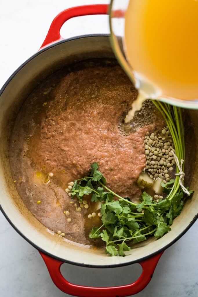 Broth being poured into a pot to make lentejas.