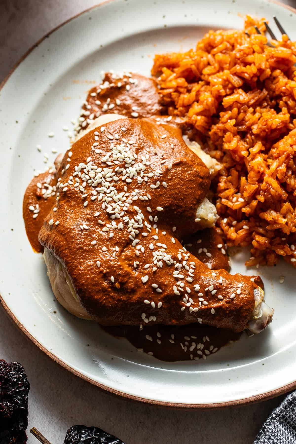 Mole spooned on a chicken leg quarter and garnished with sesame seeds.