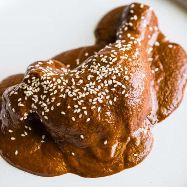 Mole sauce on chicken garnished with sesame seeds.