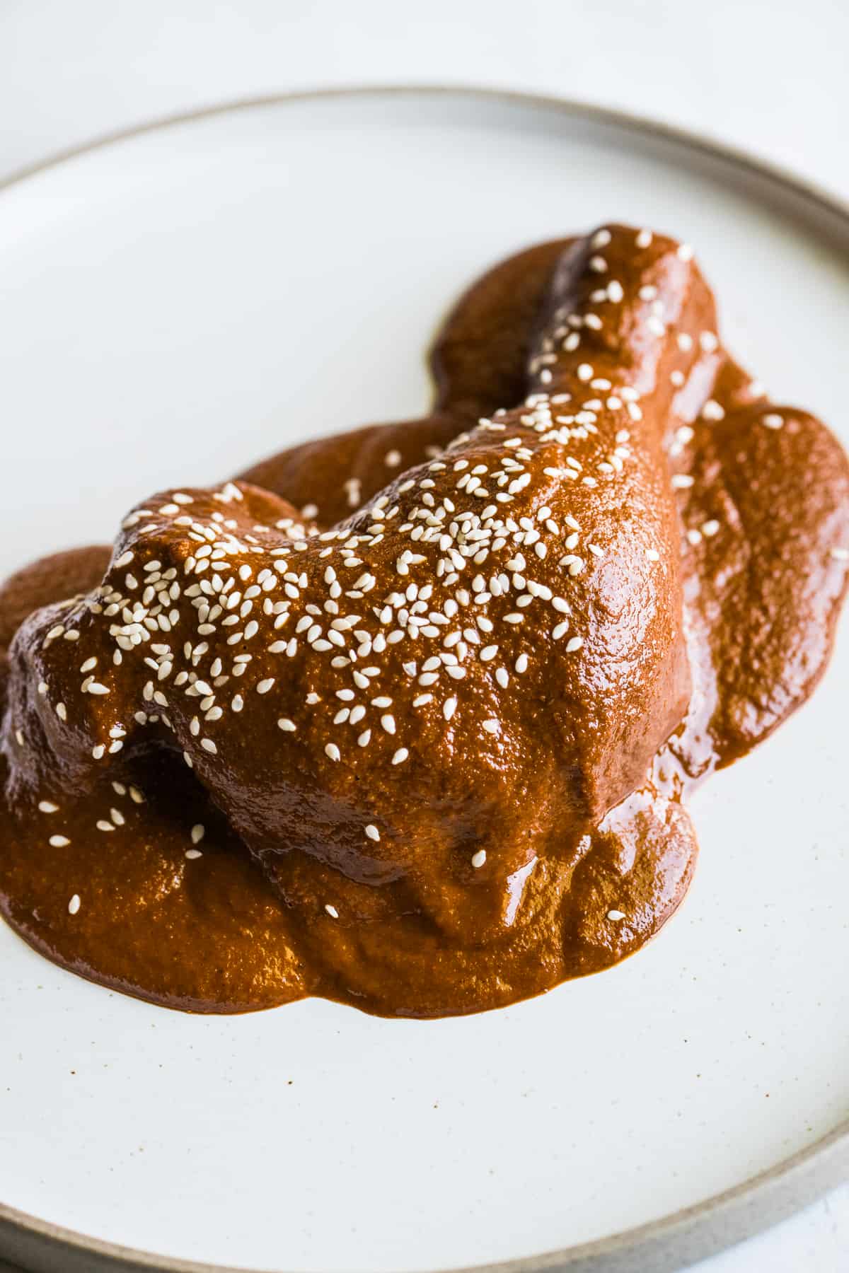 Mole sauce on chicken garnished with sesame seeds.