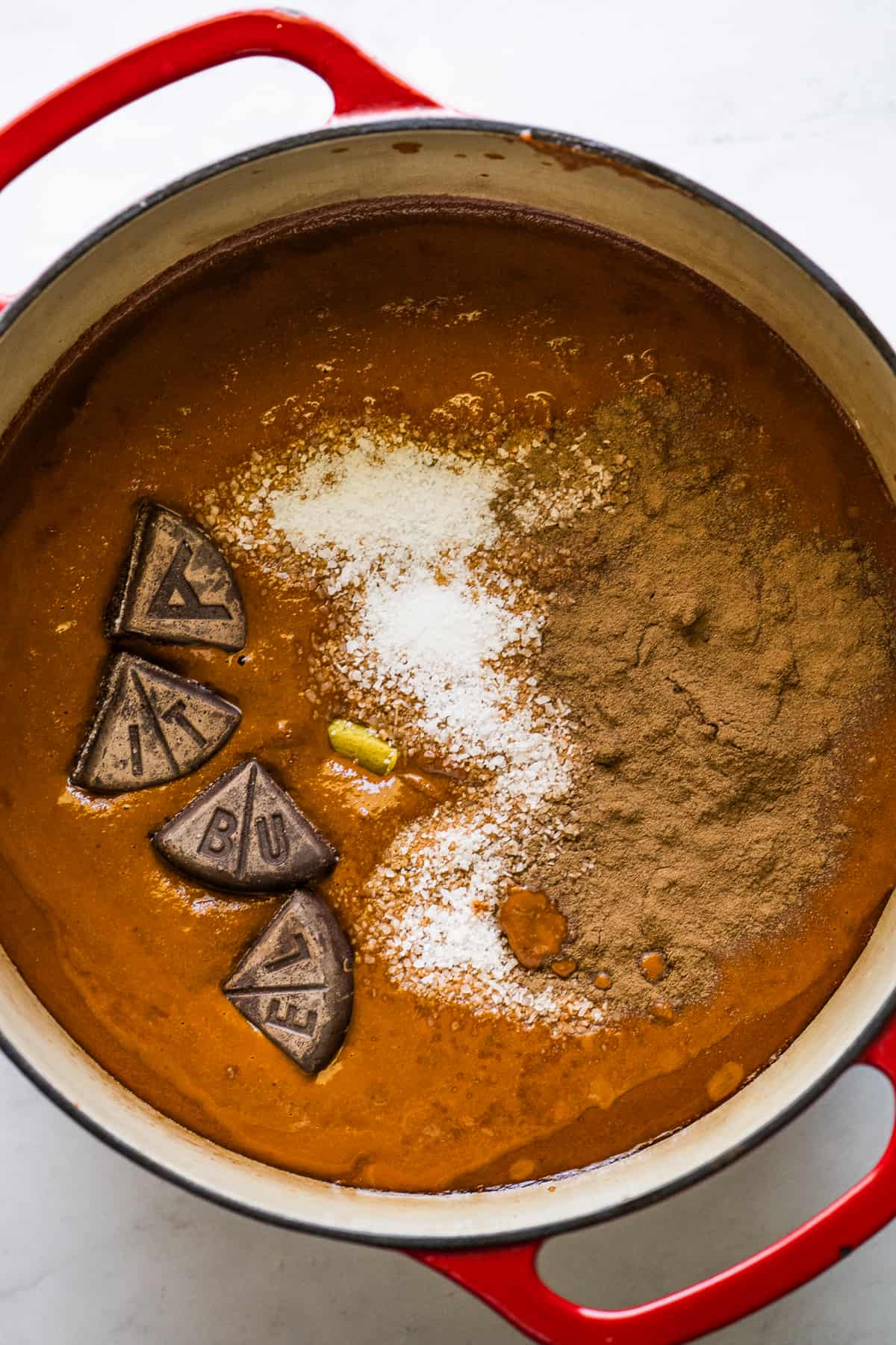 Mole sauce in a pot being combined with Mexican chocolate, cinnamon, and more.