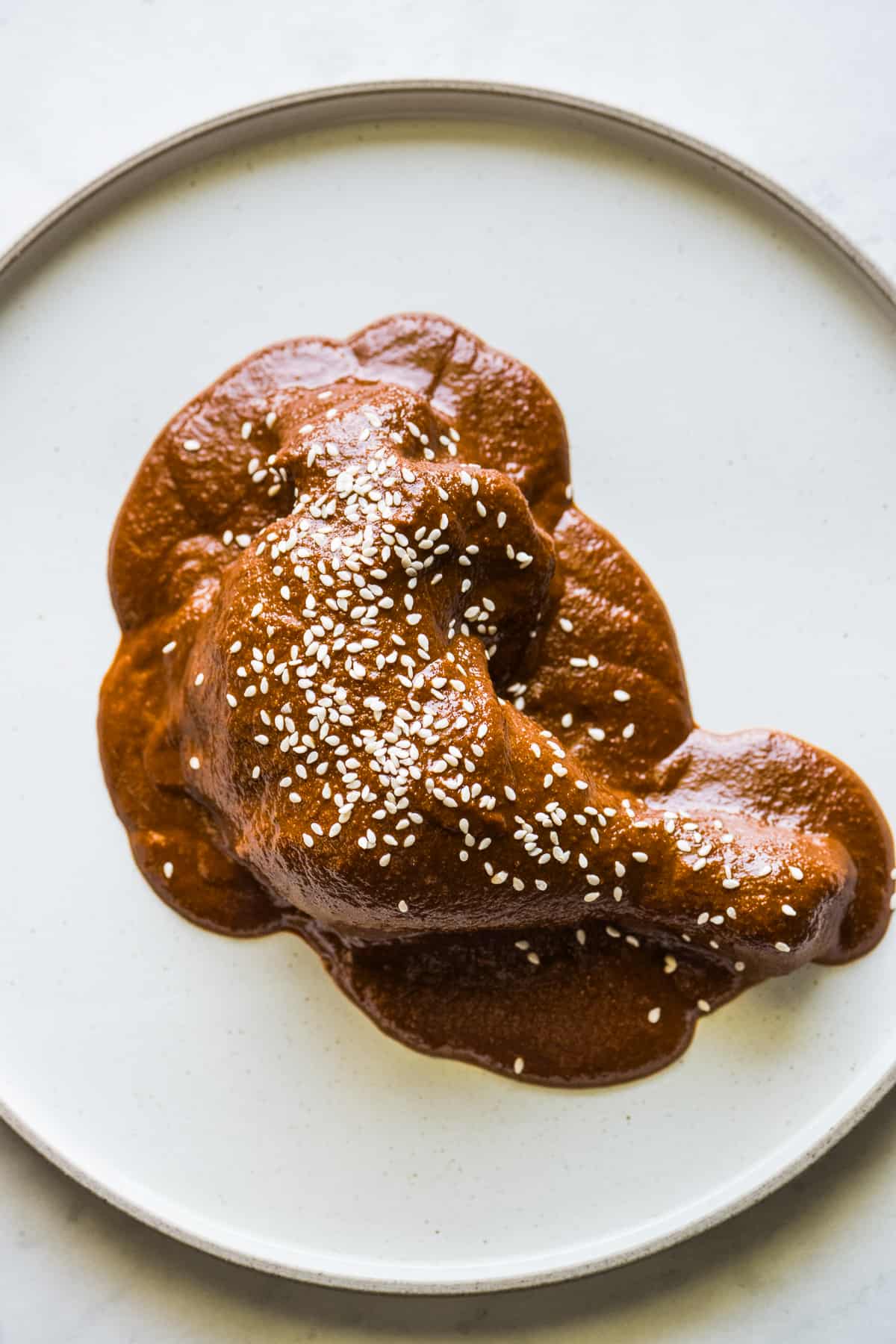 Mole sauce, or mole poblano, on a chicken leg and garnished with sesame seeds.