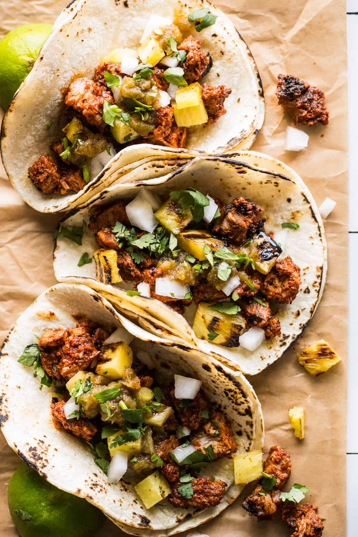 Tacos al pastor topped with grilled pineapple, cilantro, and white onion.