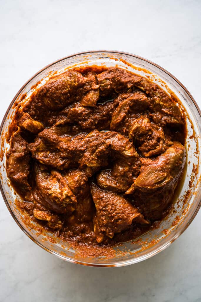 Marinated pork shoulder for tacos al pastor in a bowl.