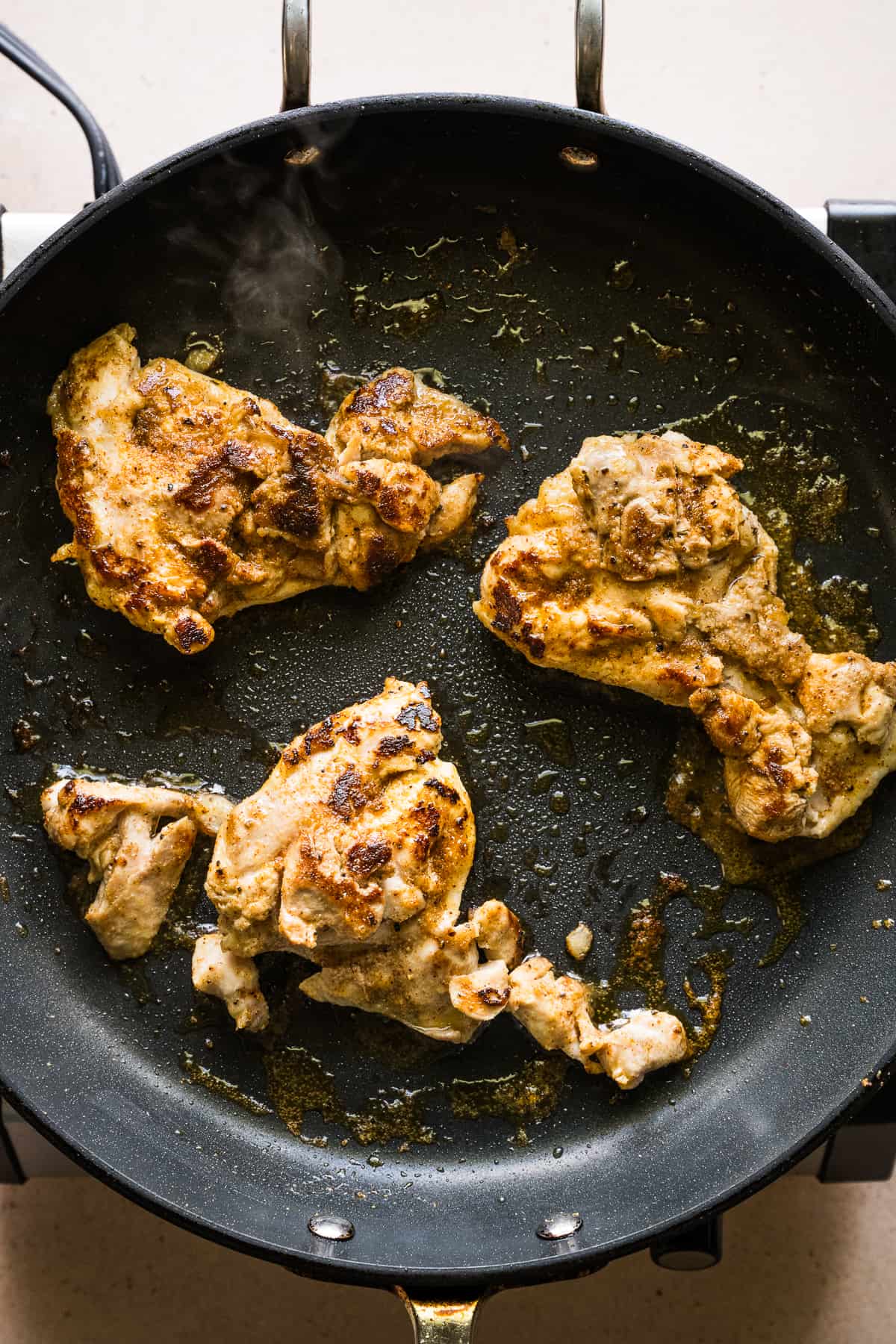 Chicken being cooked in a skillet.