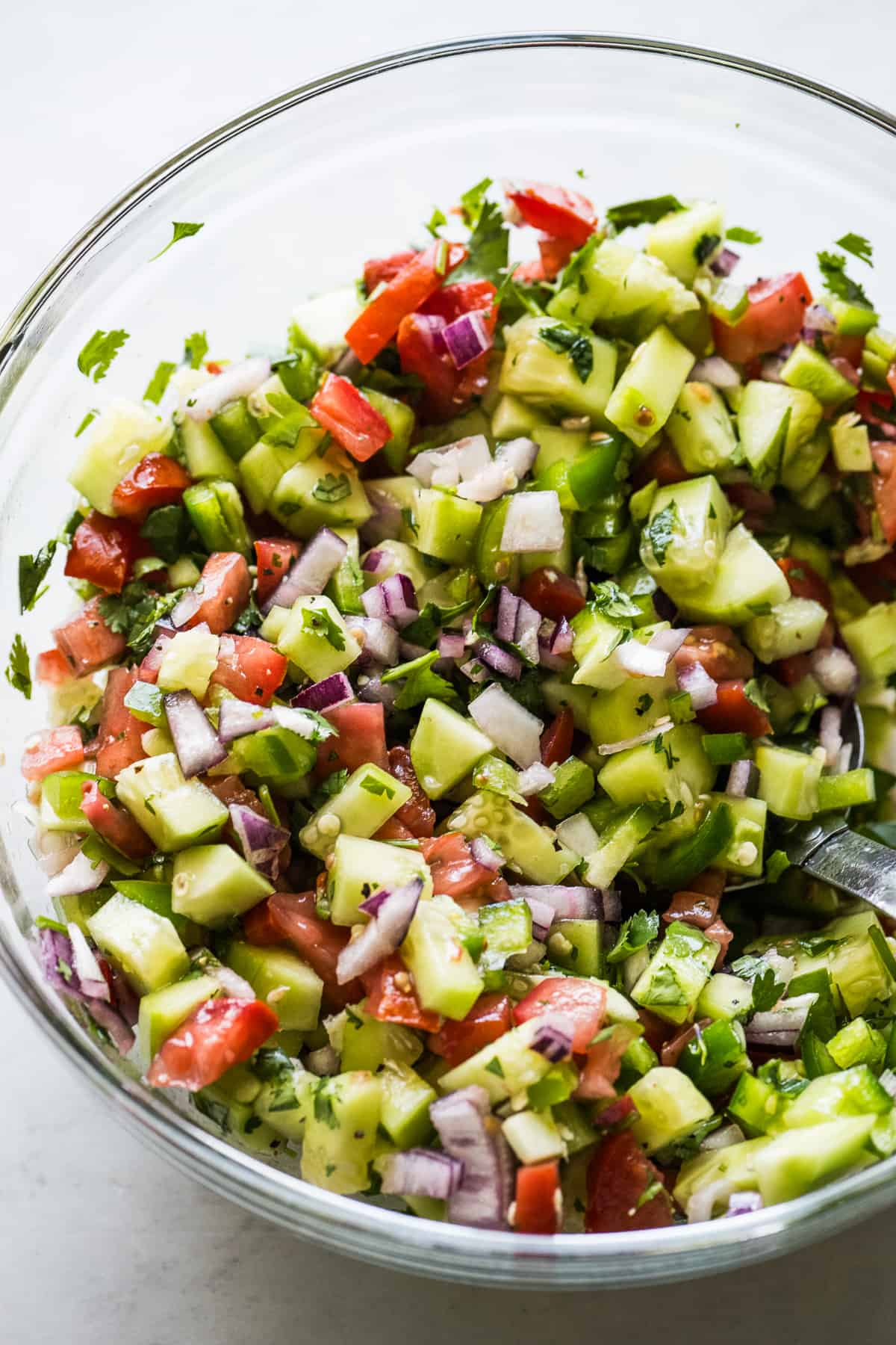 A glass bowl filled with cucumber salsa ready to be served.