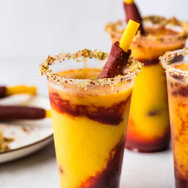 Mangonadas in clear plastic cups with a tamarind candy straws.