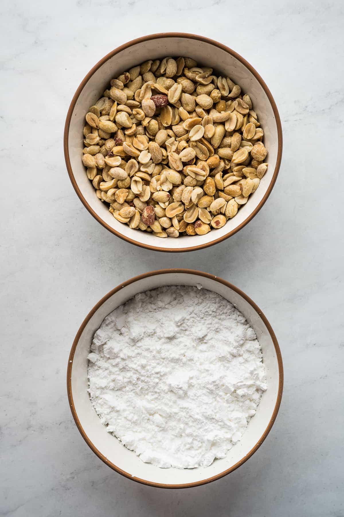 Ingredients for mazapan in 2 bowls - roasted peanuts and powdered sugar.