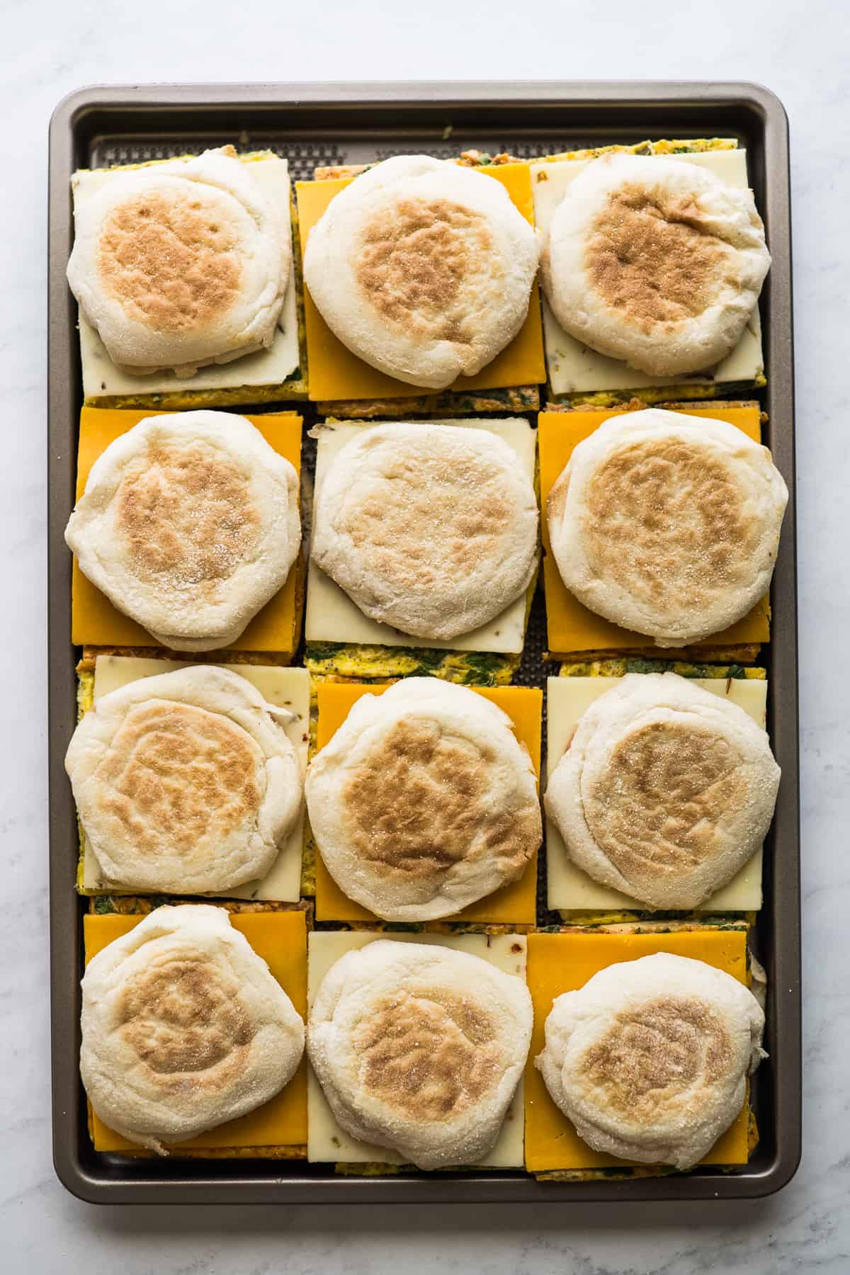 12 breakfast sandwiches on a sheet pan ready to be served or wrapped and frozen.