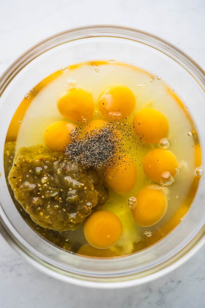 Eggs, salsa verde, salt, and black pepper in a bowl.