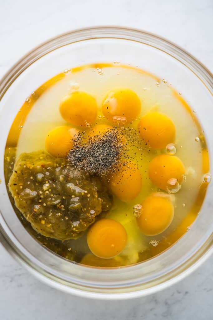 Eggs, salsa verde, salt, and black pepper in a bowl.