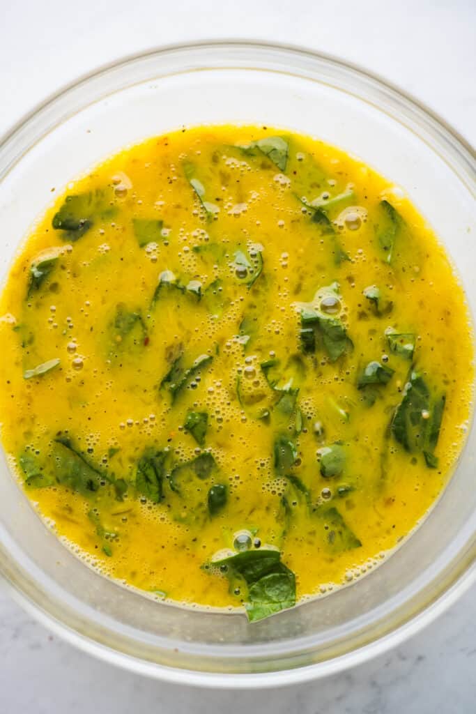 Whisked eggs, salsa, and spinach in a bowl.