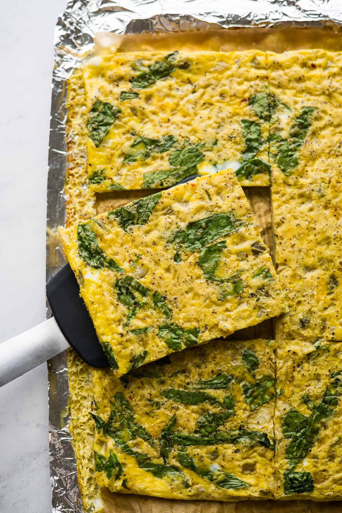 Baked sheet pan scrambled eggs cut into a square to put on a breakfast sandwich.