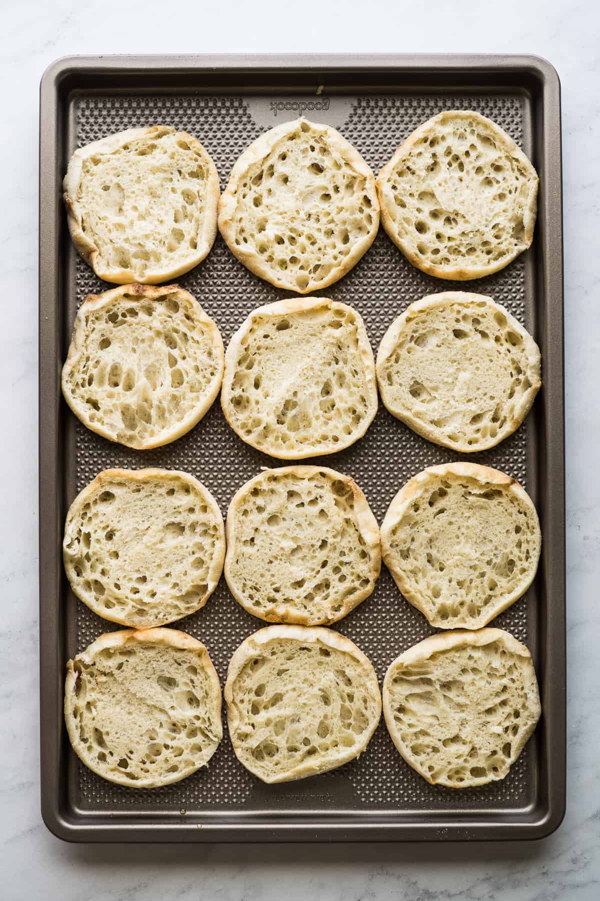 12 English muffin halves on a sheet pan.