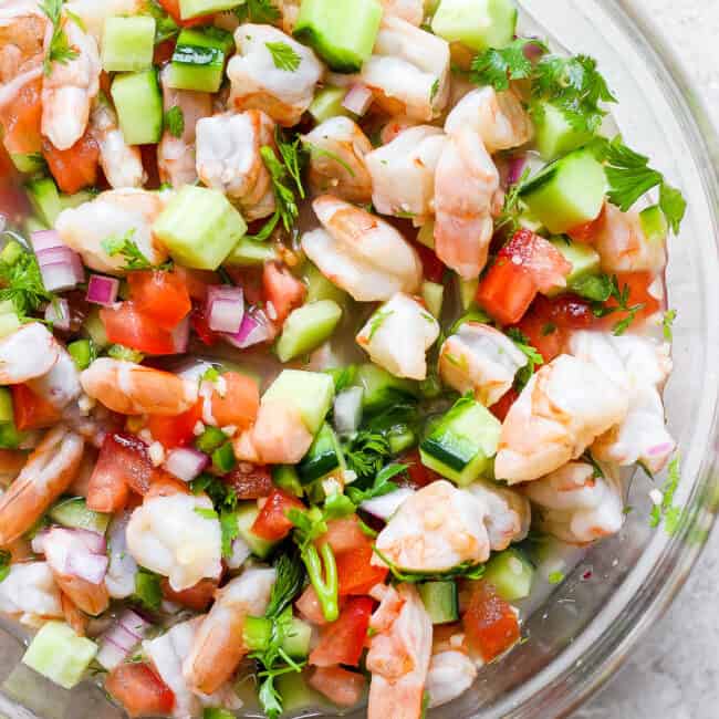 A bowl of ceviche made with shrimp, avocado, tomatoes, cilantro, red onion, and citrus juices.