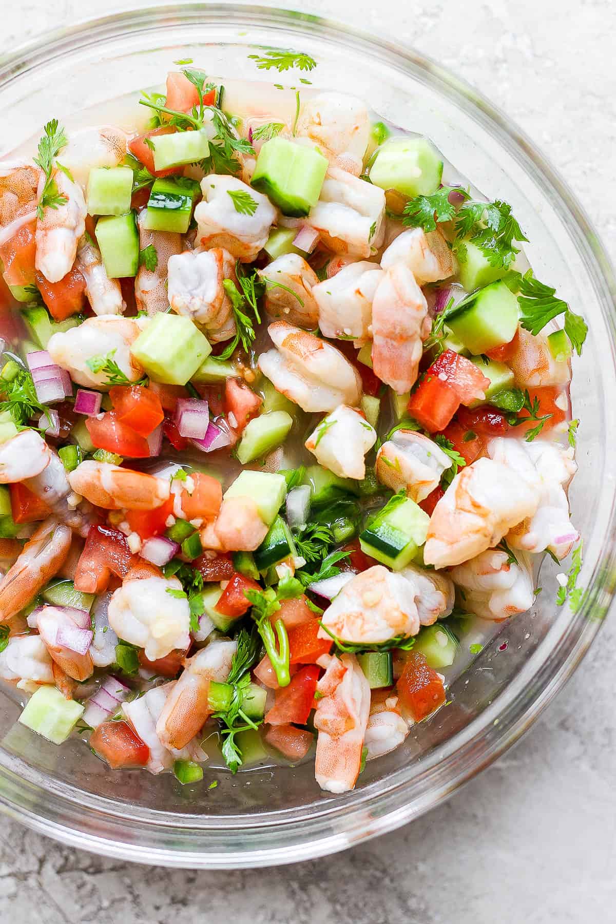 A bowl of ceviche made with shrimp, avocado, tomatoes, cilantro, red onion, and citrus juices.