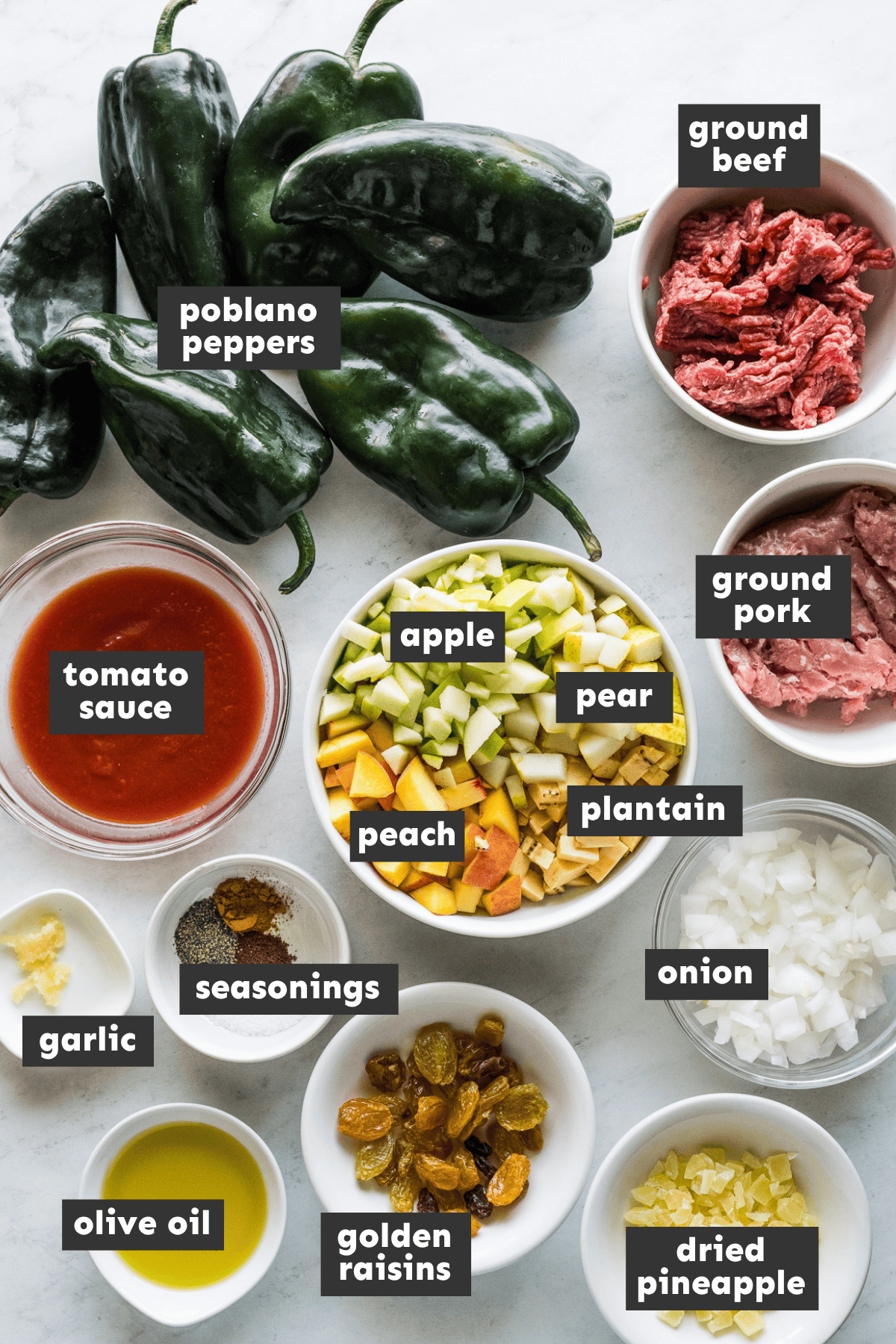 Ingredients for chiles en nogada laid out on a table including poblano peppers, fruit, and walnuts.