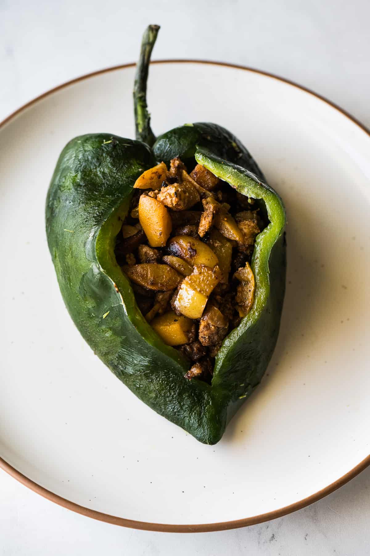 A roasted and peeled poblano pepper stuffed with chile en nogada filling.