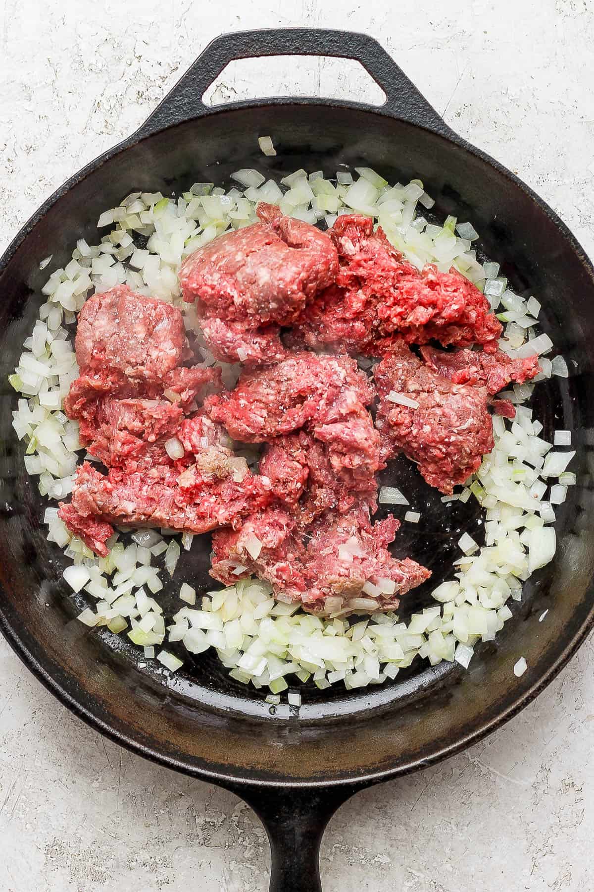 Ground beef and onions cooking in a skillet.