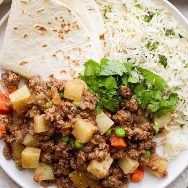Mexican picadillo on a plate with rice and flour tortillas.