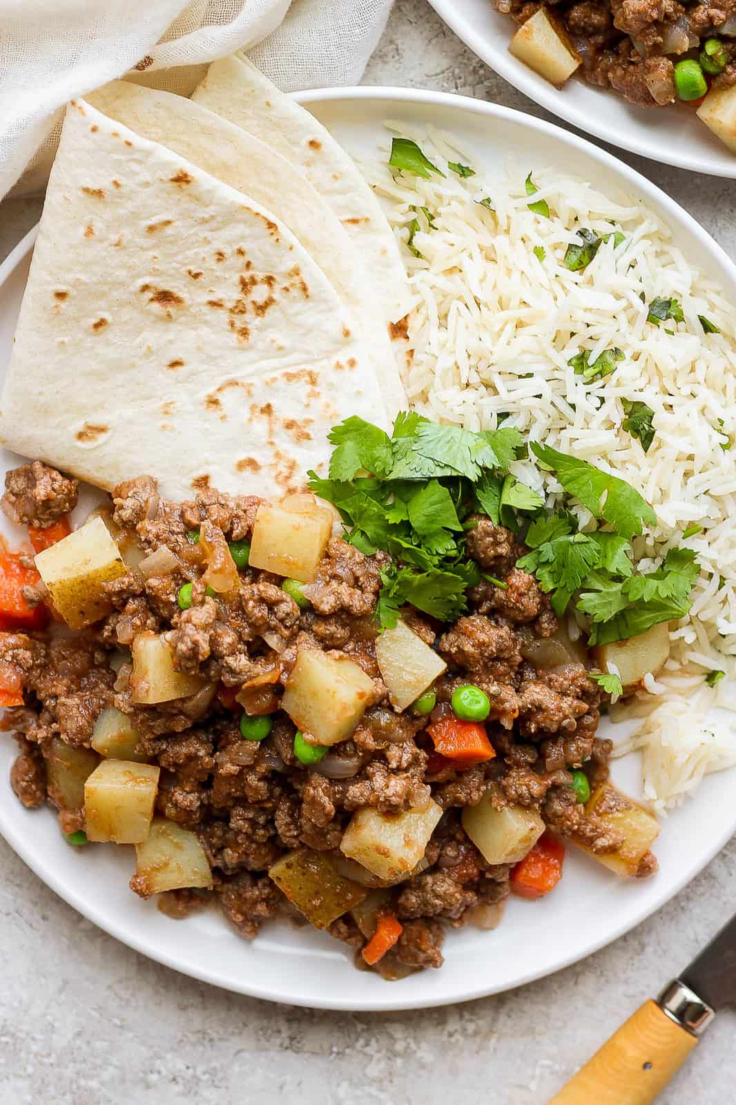 Mexican picadillo on a plate with rice and flour tortillas.