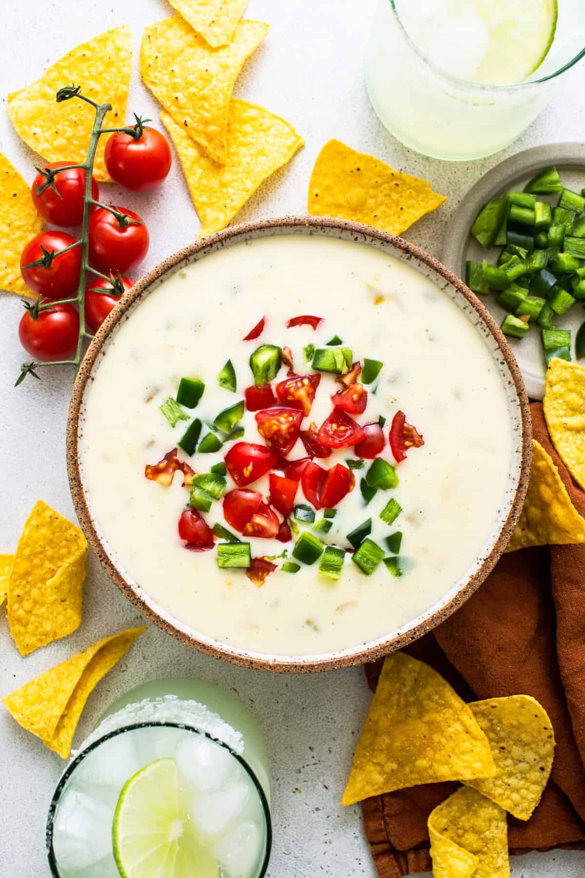 Queso blanco in a bowl topped with diced tomatoes and jalapeños.