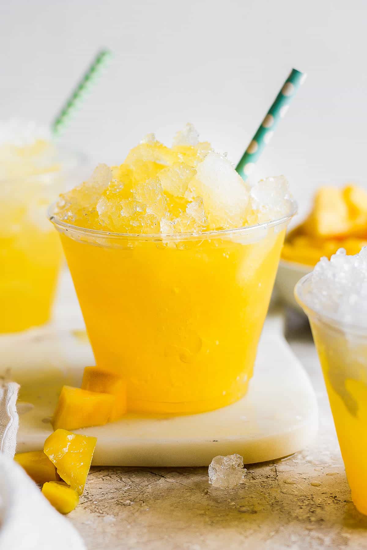 Raspados Mexicanos shaved ice in a cup with a straw made with a sweet mango syrup