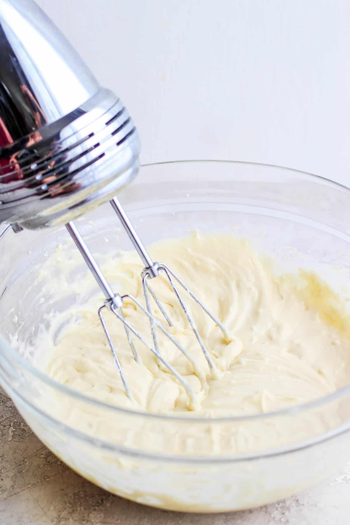 A hand mixer mixing the cheesecake filling for sopapilla cheesecake.