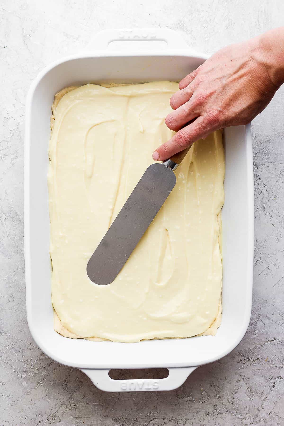 Cheesecake filling being spread out on top of the crescent roll dough.