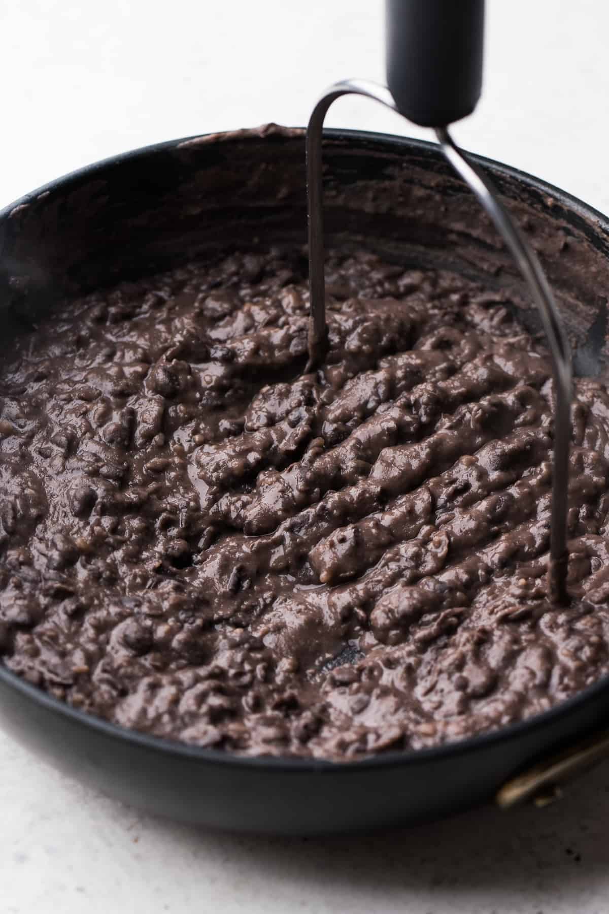 Mashed black beans in a skillet.