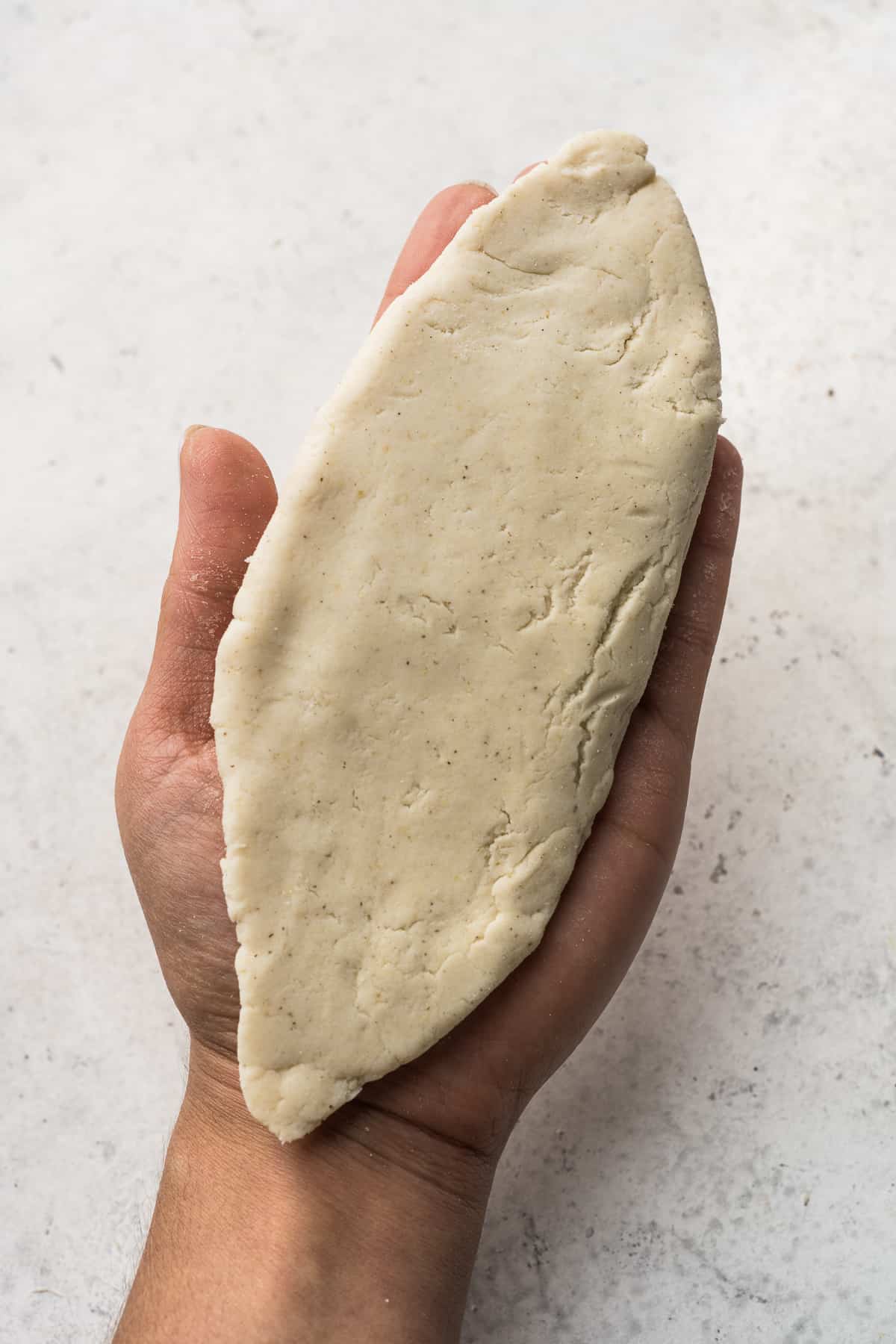 A shaped tlacoyo in the palm of a hand.