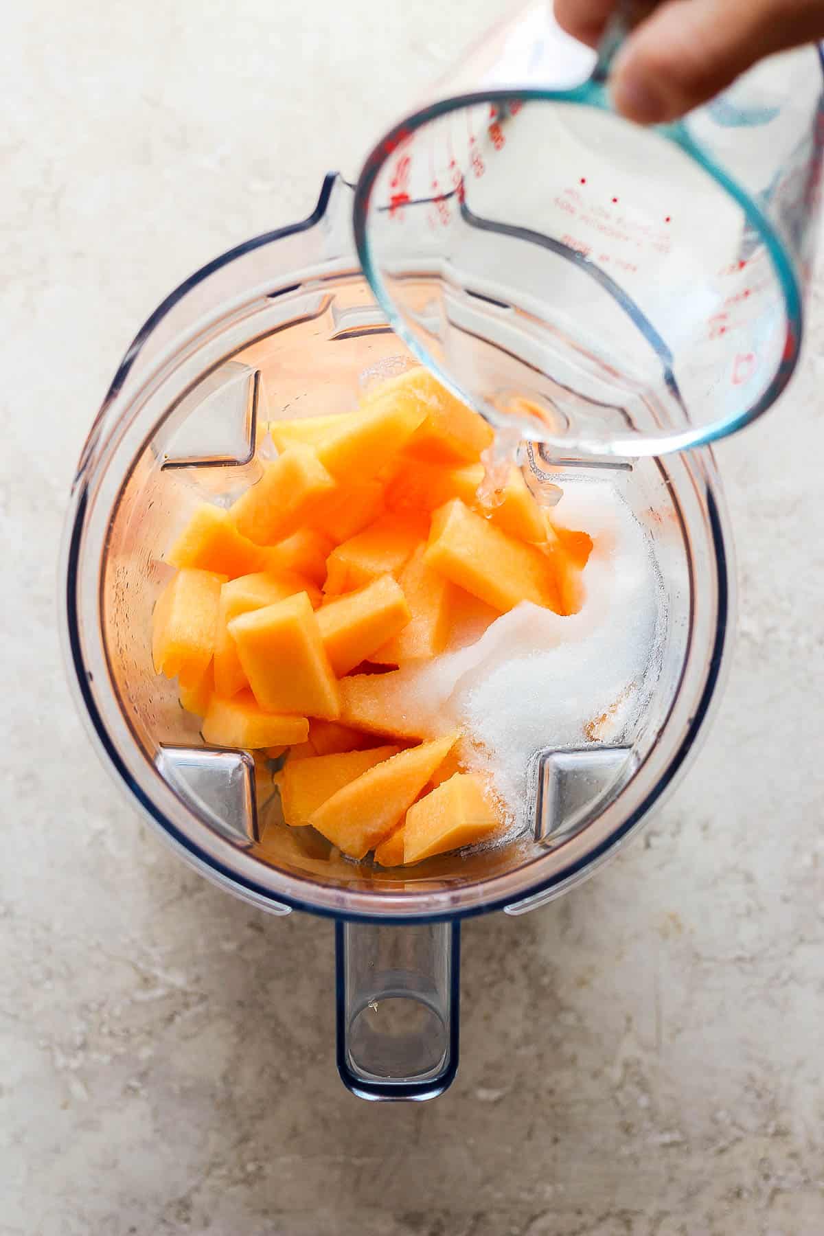 Cantaloupe, sugar, and water in a blender.