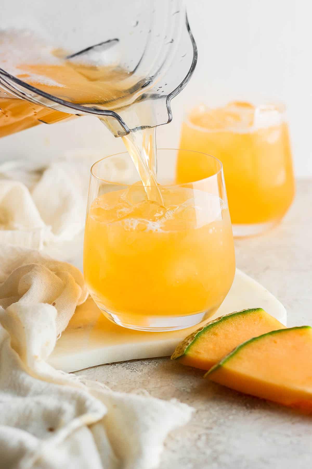 Agua de melon being poured into a glass for serving.