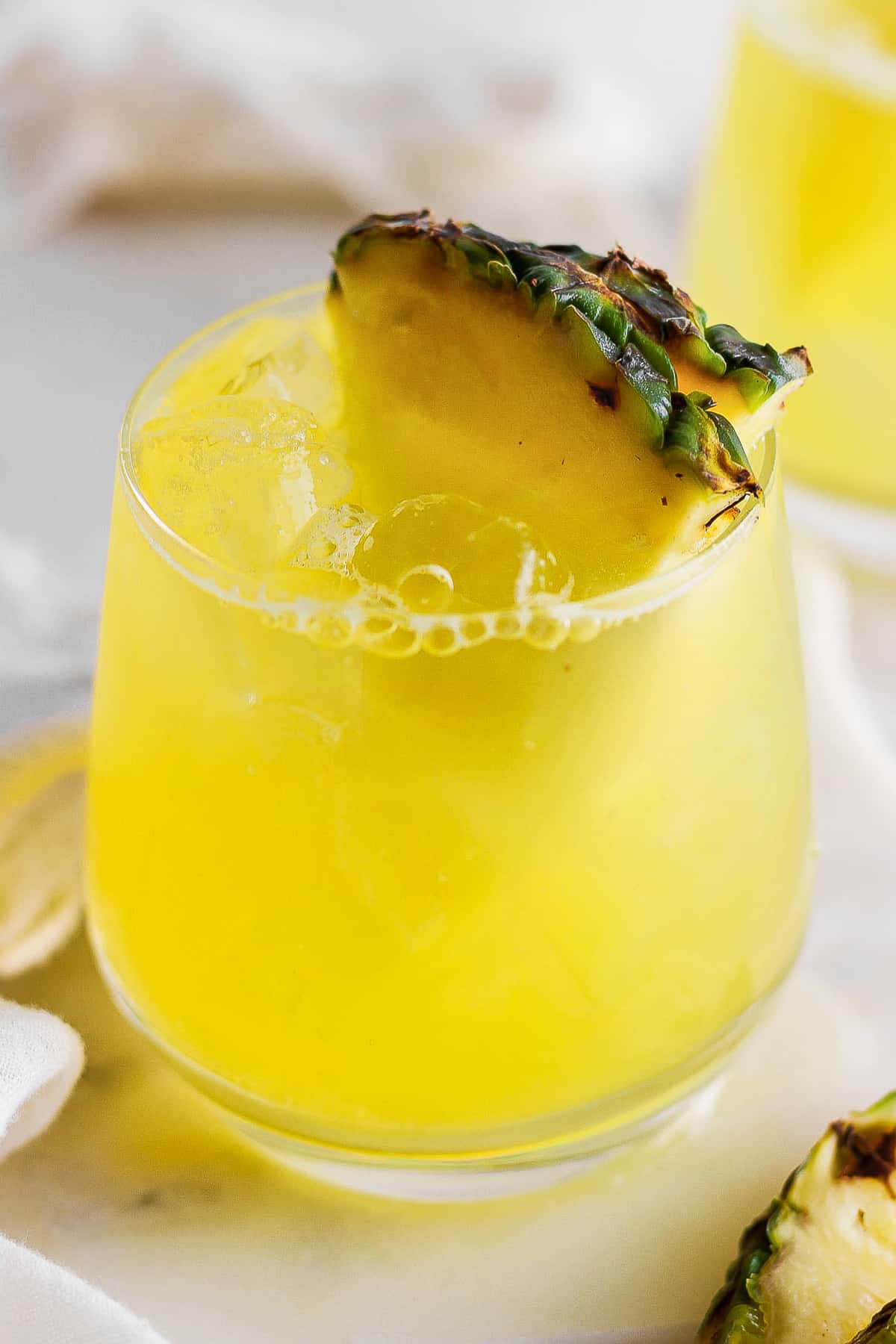 Agua de pina in a glass with ice garnished with a pineapple wedge.