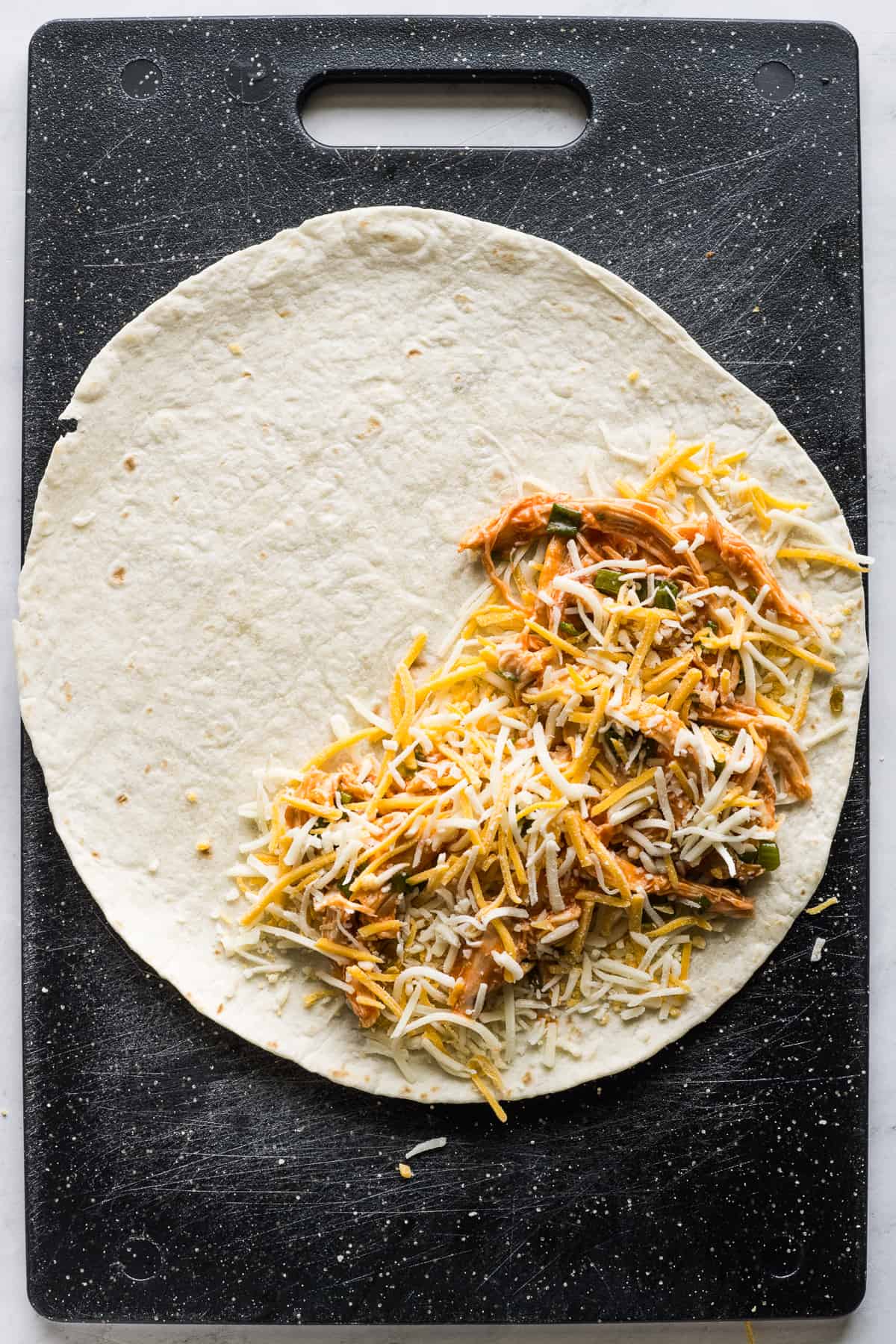 A flour tortilla filled with buffalo chicken and shredded cheese.