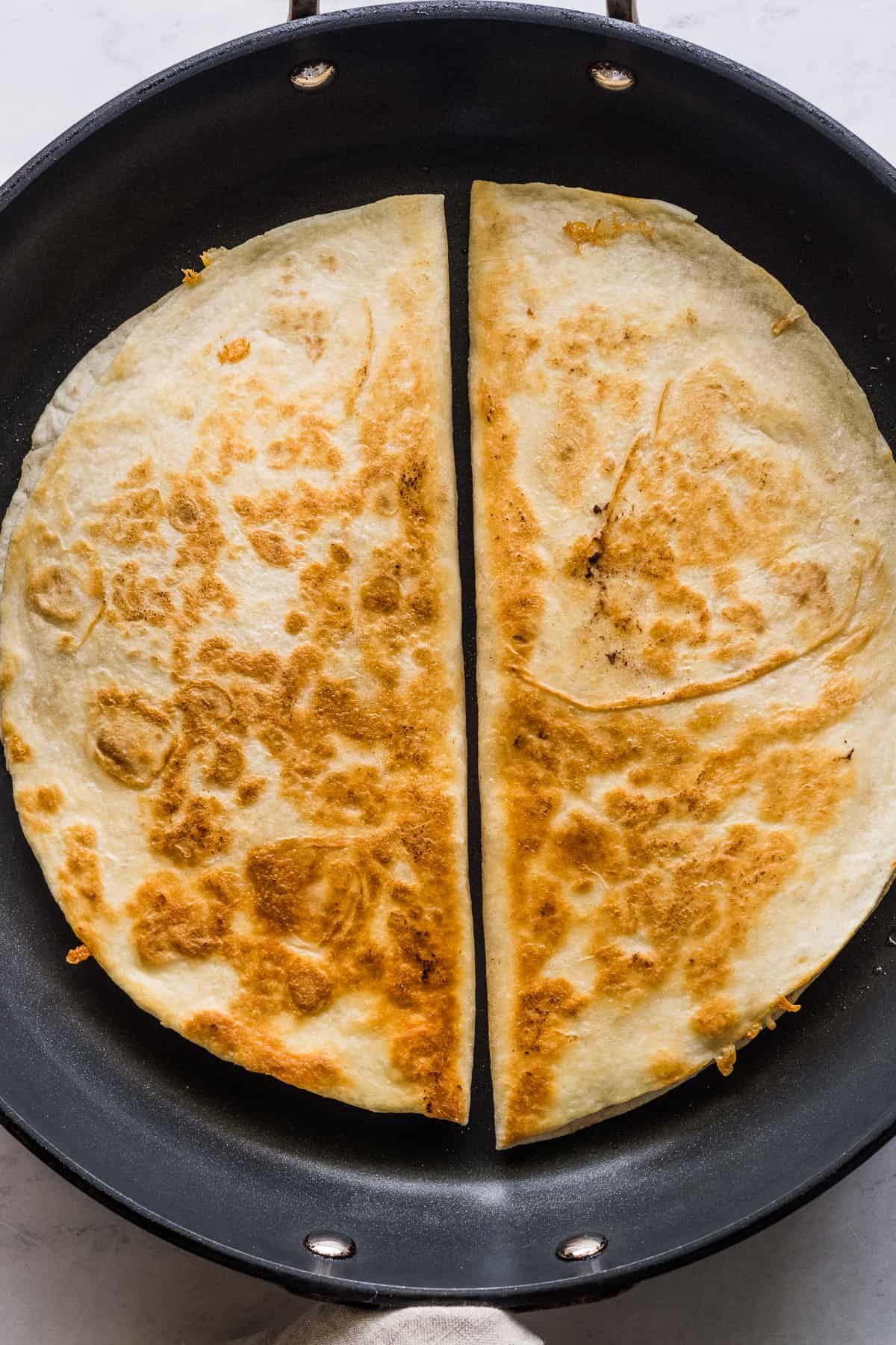 Buffalo chicken quesadillas being cooked in a large skillet.