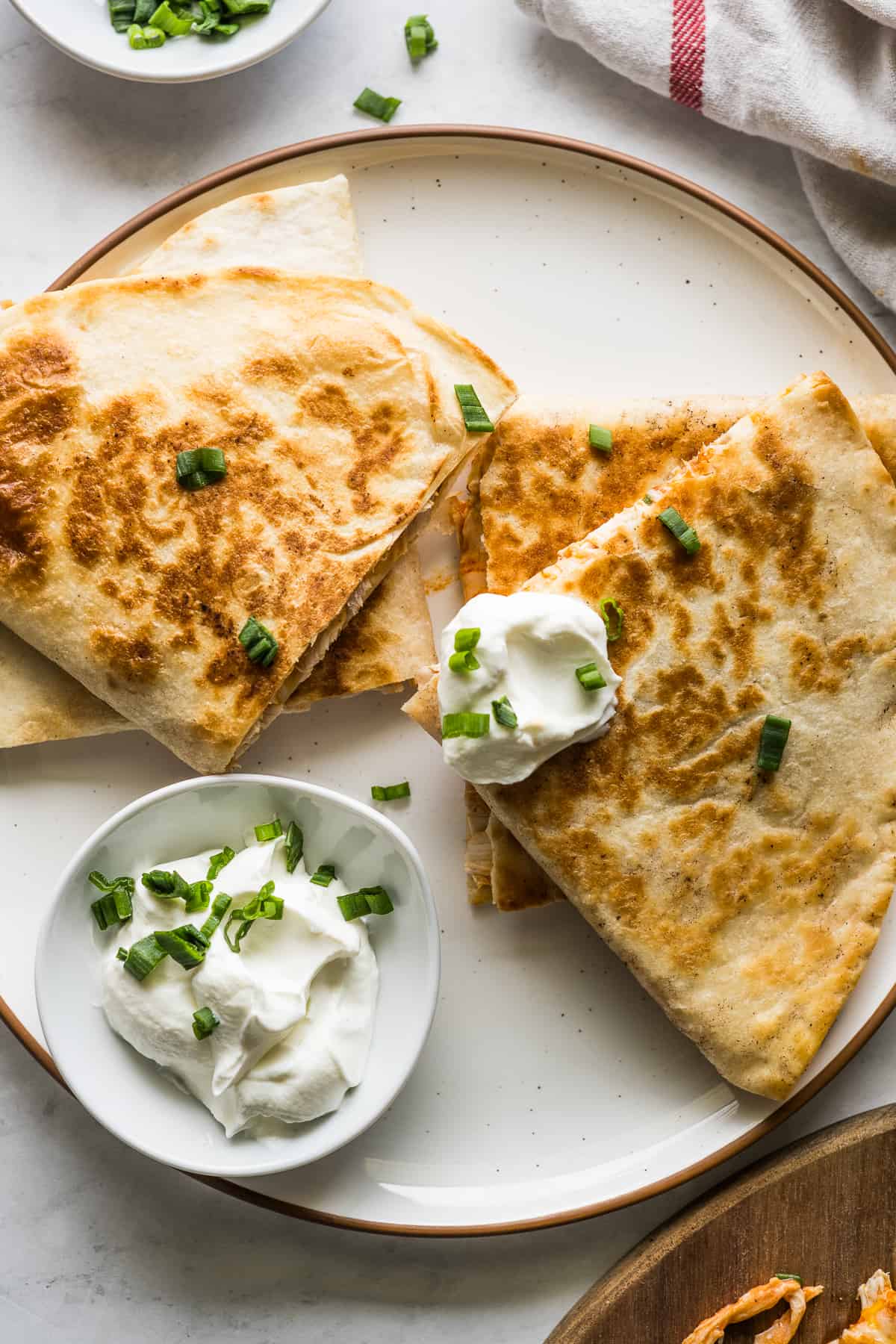 Buffalo chicken quesadillas on a plate served with sour cream.