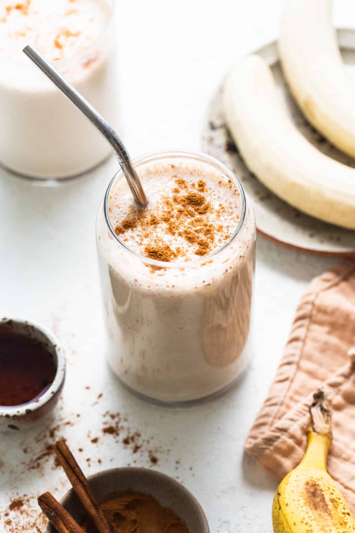 A licuado de platano in a glass cup garnished with ground cinnamon