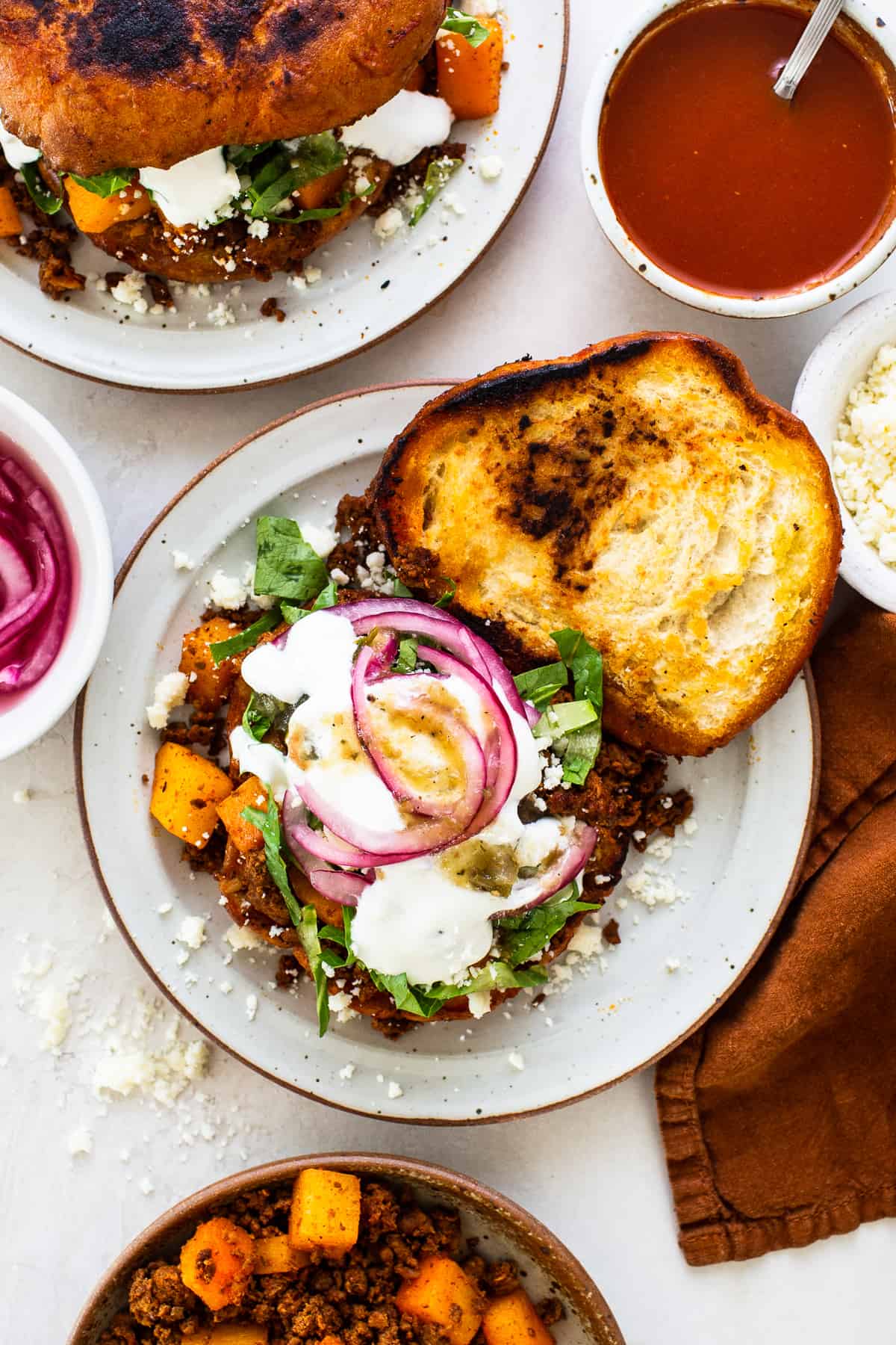 A pambazo with a chorizo and potato filling, topped with lettuce, mexican crema, red onions, and salsa verde.