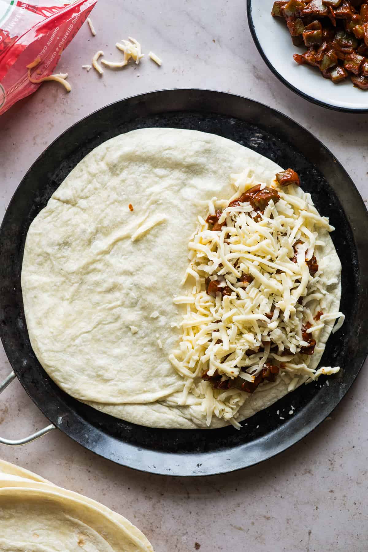 A flour tortilla layered with Chihuahua Mexican cheese, nopales en chile rojo, and more cheese.