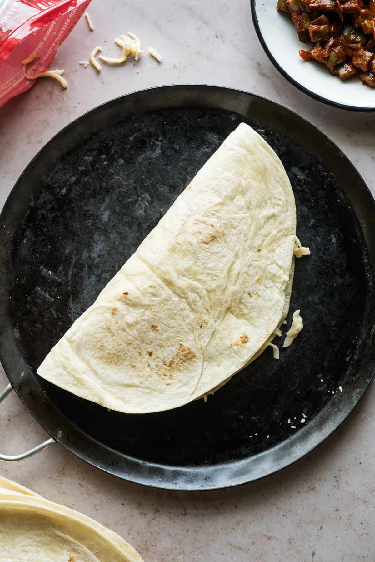 An uncooked quesadilla on a comal.